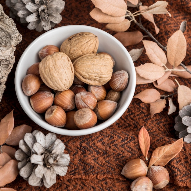 Gratis foto hoge hoek van kom met kastanjes en herfstbladeren