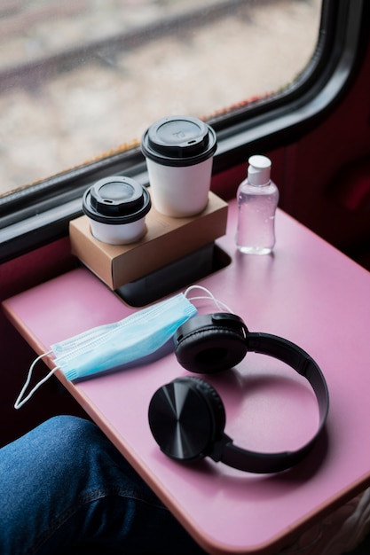 Hoge hoek van koptelefoon en medisch masker op treintafel