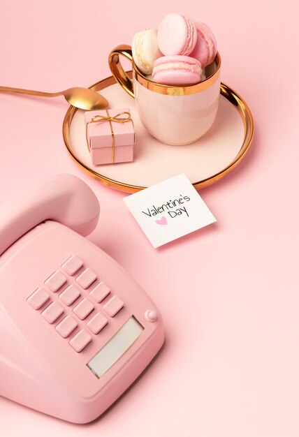 Hoge hoek van macarons in gouden beker voor Valentijnsdag met roze telefoon