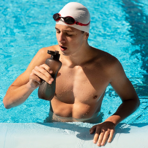 Hoge hoek van mannelijke zwemmer drinkwater om gehydrateerd te blijven