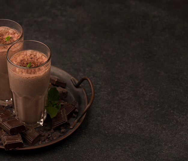 Hoge hoek van milkshakeglazen op dienblad met chocolade en exemplaarruimte