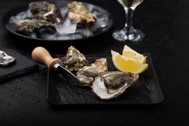 Hoge hoek van oesters op plaat met mes en citroenplakken