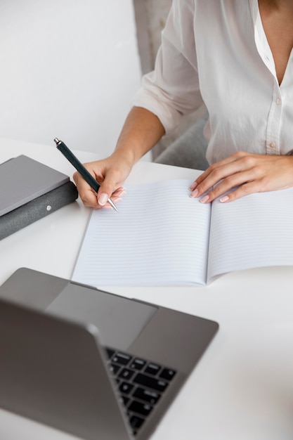 Hoge hoek van onderneemster die met notitieboekje en laptop werkt