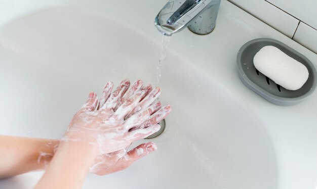 Hoge hoek van persoon die hun handen in de badkamers wast