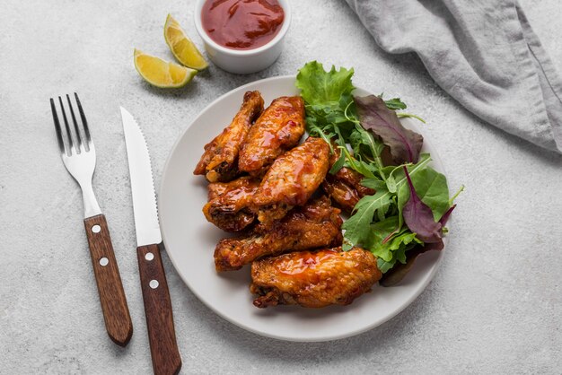 Hoge hoek van plaat met gebakken kip en salade met saus en bestek