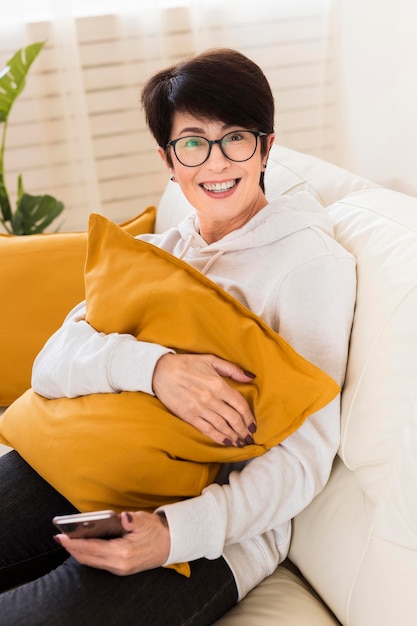 Gratis foto hoge hoek van smiley vrouw op sofa met smartphone