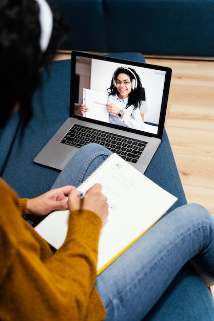 Hoge hoek van tienermeisje met koptelefoon tijdens online school