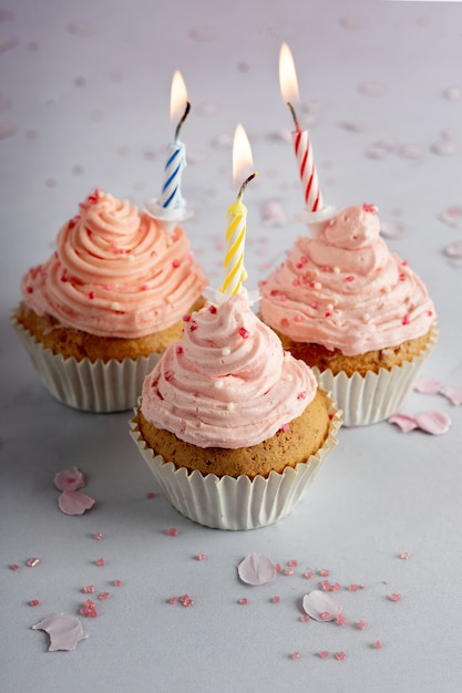 Hoge hoek van verjaardag cupcakes met suikerglazuur en aangestoken kaarsen