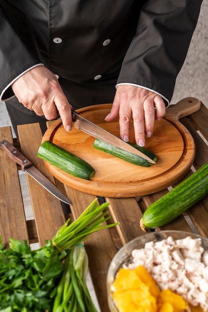 Hoge hoek van vrouwelijke chef-kok snijden komkommers