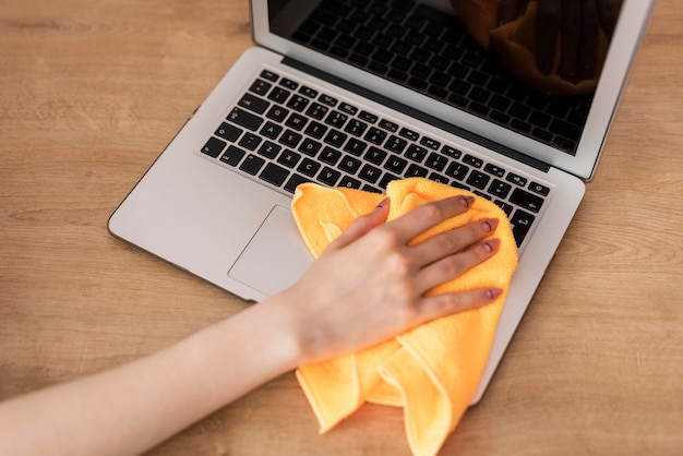 Hoge hoek van vrouwen schoonmakende laptop met doek