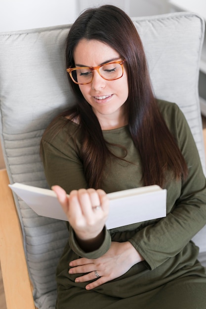 Hoge hoek vrouw leesboek zittend op een stoel