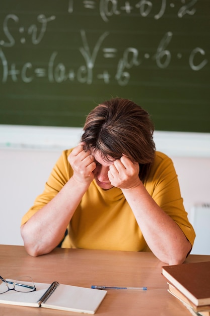 Hoge hoek vrouwelijke leraar aan bureau moe