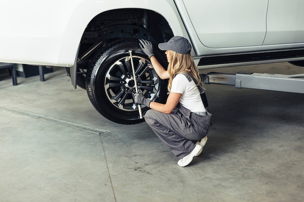 Gratis foto hoge hoek vrouwelijke monteur veranderende auto wielen