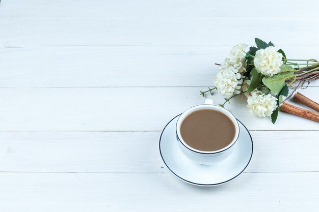 Hoge hoek weergave kopje koffie met bloemen, kaneel op witte houten plank achtergrond. horizontaal