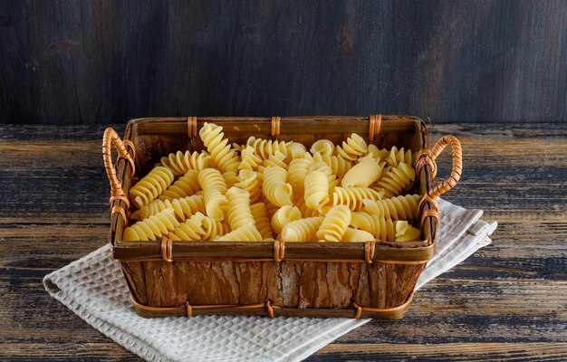 Hoge hoek weergave macaroni pasta in lade op doek en houten achtergrond. horizontaal