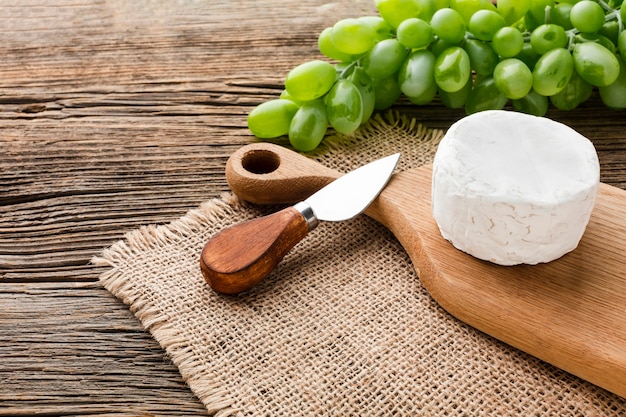 Gratis foto hoge hoekcamembert en druiven op houten snijplank