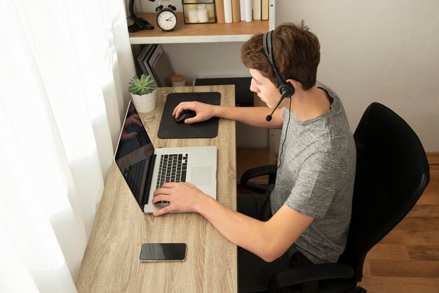 Hoge hoekjongen die een online spel met zijn vrienden speelt