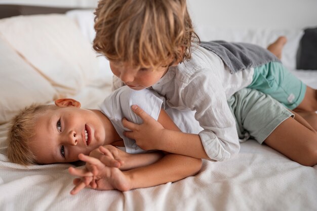 Hoge hoekkinderen die in bed spelen