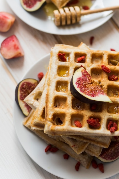 Gratis foto hoge hoekmening van belgische wafels; honing met vijgen fruit in plaat