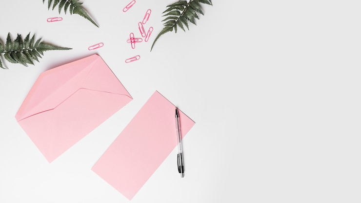 Gratis Foto hoge hoekmening van envelop; pen; kunstmatige varens en paperclips op witte achtergrond