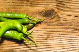 Gratis foto hoge hoekmening van groene chilipepers op houten achtergrond