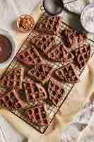 Gratis foto hoge hoekmening van heerlijke chocoladewafels op een net op de tafel in de buurt van de ingrediënten