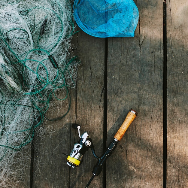 Gratis foto hoge hoekmening van hengel en net op houten plank