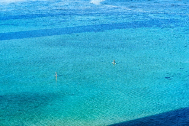 Hoge hoekmening van mensen die in de zuivere blauwe oceaan surfen