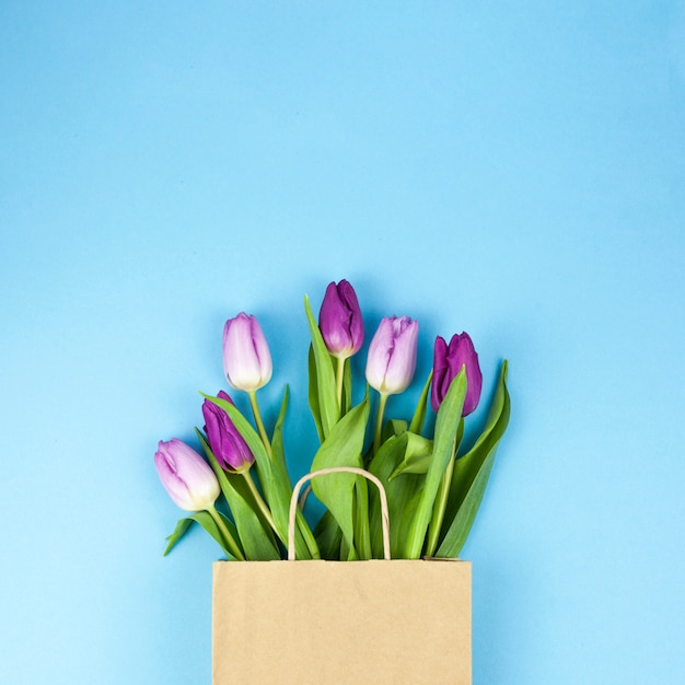 Hoge hoekmening van paarse tulpenbloemen op bruine zak tegen blauwe achtergrond