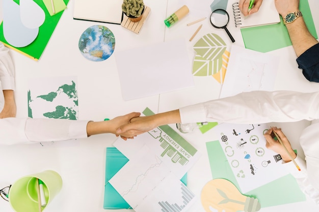 Gratis foto hoge hoekmening van twee zakenmensen schudden handen over bureau