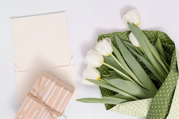 Gratis foto hoge hoekmening van witte tulp bloemen boeket; geschenkdoos met blanco papier op witte achtergrond