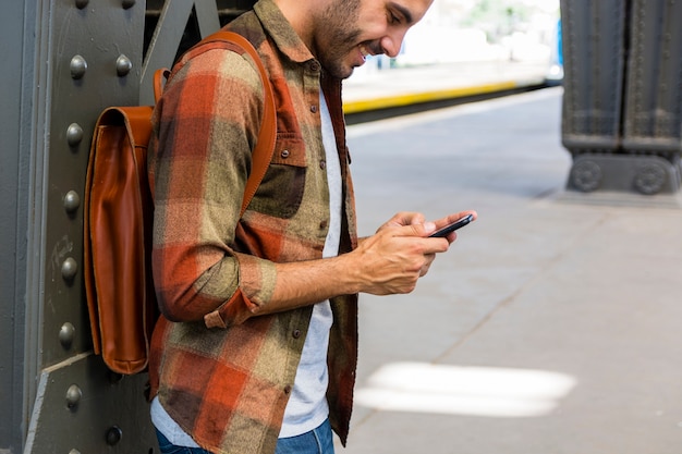 Hoge hoekmens bij metro die telefoon met behulp van