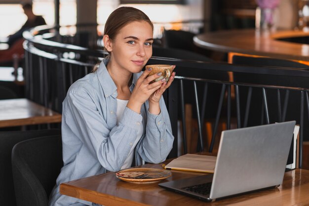 Hoge hoekvrouw bij restaurant het drinken koffie