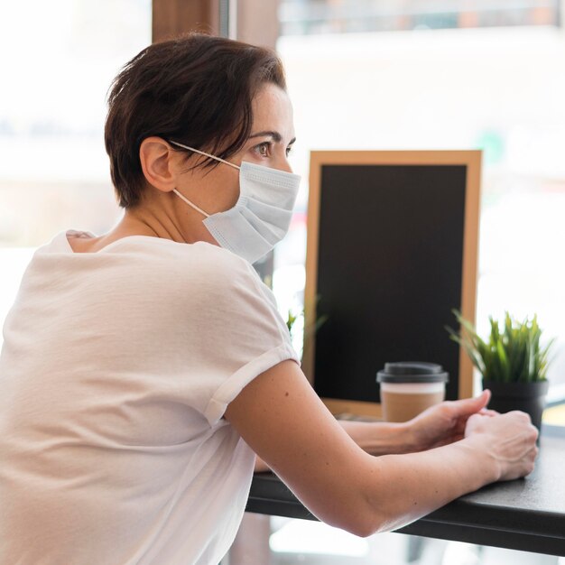 Hoge hoekvrouw bij terras dat masker draagt