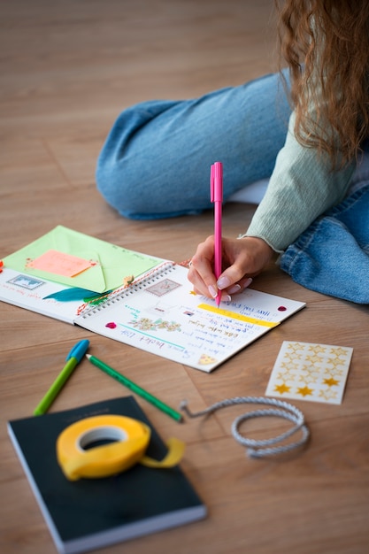 Hoge hoekvrouw die creatieve journaling doet