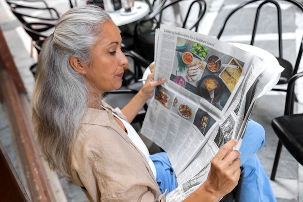 Hoge hoekvrouw die de krant leest