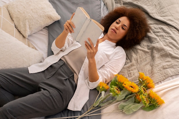 Gratis foto hoge hoekvrouw die in bed met zonnebloemen legt