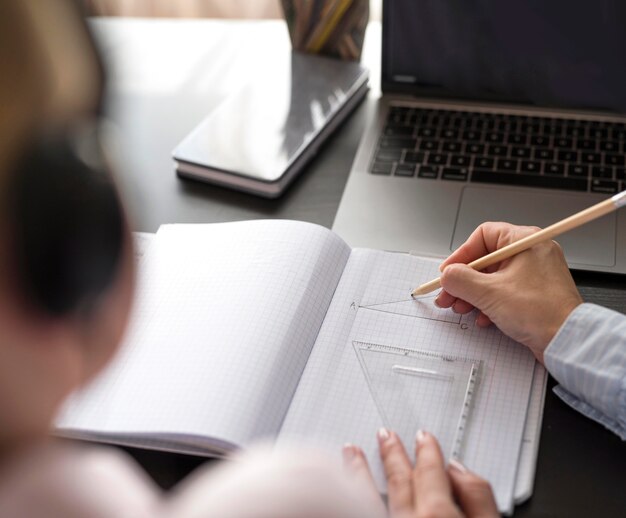 Hoge hoekvrouw die meisje helpt bij het doen van haar huiswerk