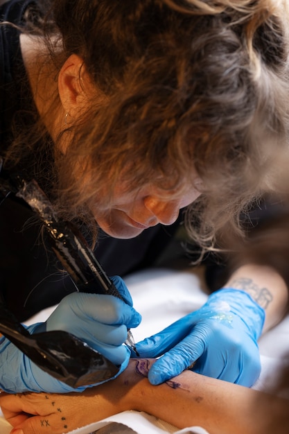 Gratis foto hoge hoekvrouw die tatoeages doet