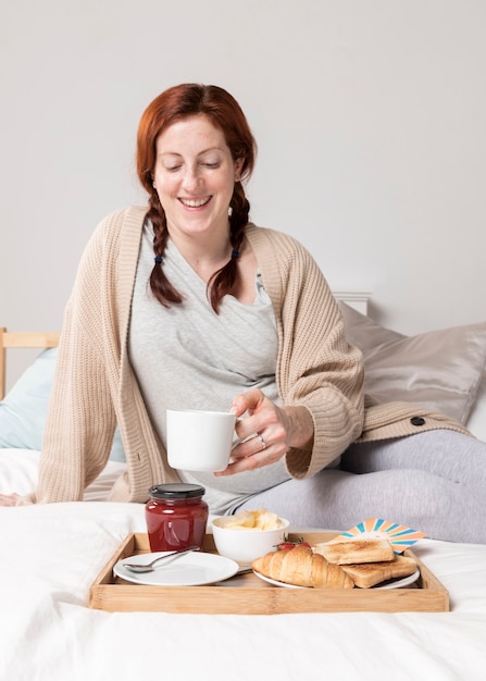 Gratis foto hoge hoekvrouw die van brunch in bed geniet