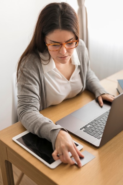 Hoge hoekvrouw die van huis aan laptop werkt