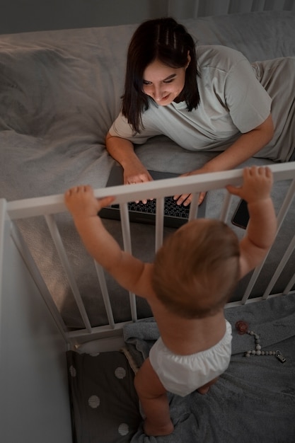 Gratis foto hoge hoekvrouw met baby die aan laptop werkt