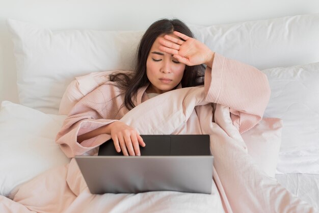 Hoge hoekvrouw op bed met laptop