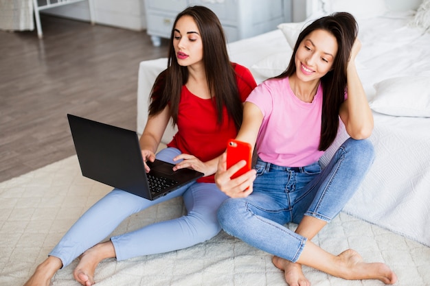 Hoge hoekvrouwen die laptop en telefoon met behulp van