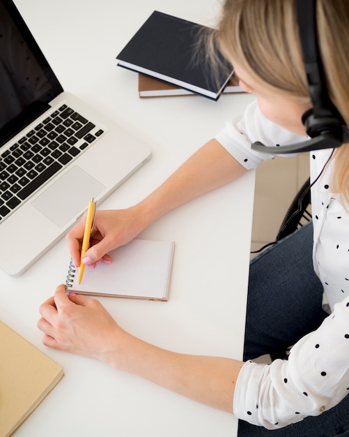 Hoge meningsvrouw die op een blocnote schrijft