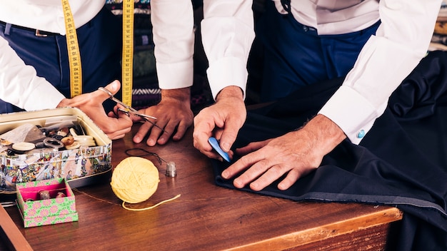 Gratis foto hoger mannelijk kleermaker die doekpatroon met krijt op workshop merken