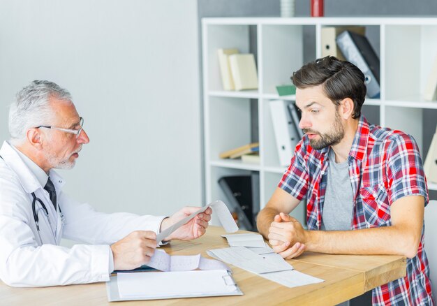 Hogere arts die met patiënt in bureau spreekt