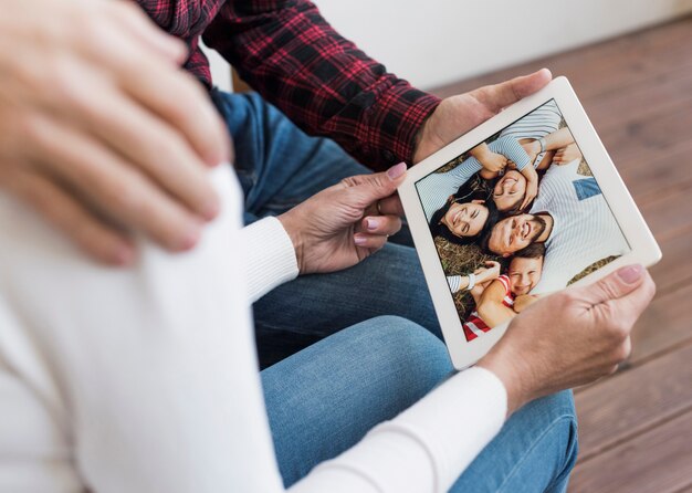 Hogere man en vrouw die door beelden op hun tablet kijken