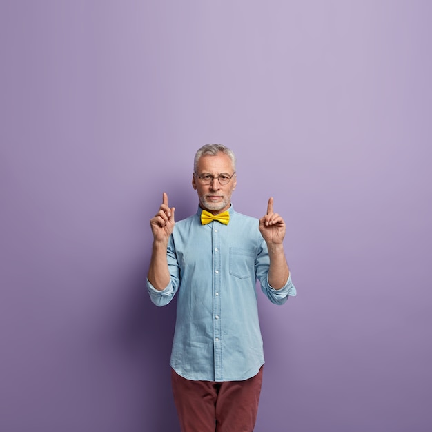 Hogere mens in denimoverhemd en gele bowtie