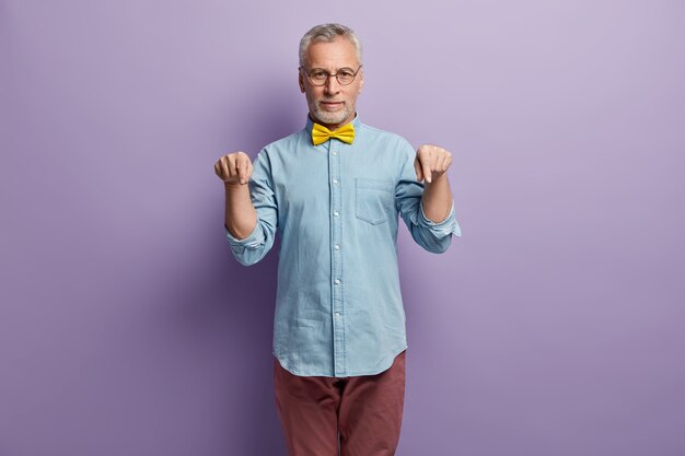 Hogere mens in denimoverhemd en gele bowtie